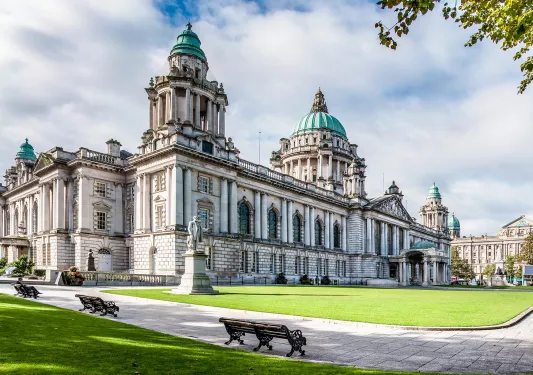 White and blue castle building with statues and green grass in the outdoor courtyard