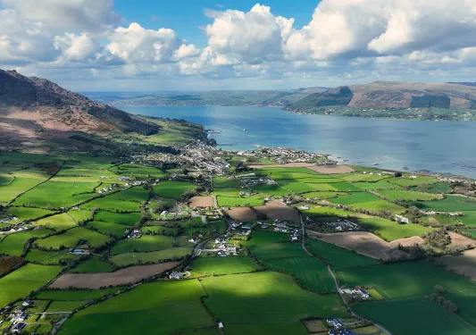 Sky view of grass fields with houses across multiple acres