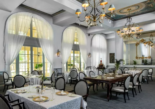 Indoor dining room with large white curtains and wine glasses on the tables
