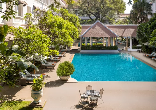 Outdoor swimming pool surrounded by reclining pool chairs
