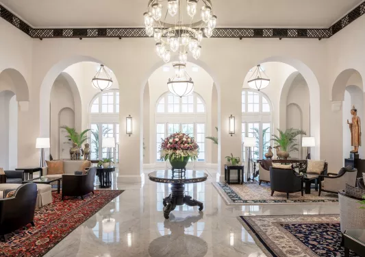Hotel lobby with chairs on either side and a table with a vase in the center