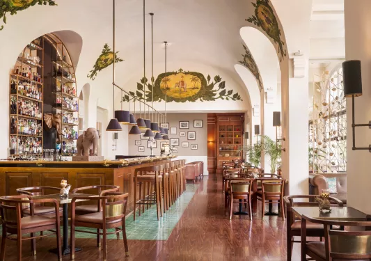 Indoor bar with wooden chairs and tables and a statue of an elephant to the left