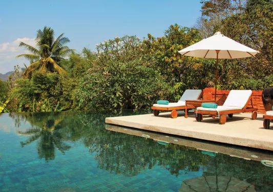 lounge chairs next to a body of water