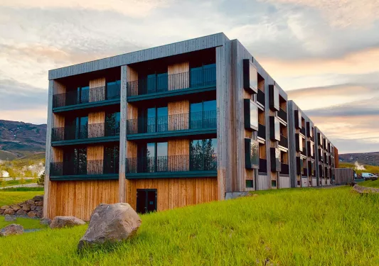 Exterior view of wooden hotel building with balconies and large mountains in the distance