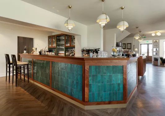Green and brown bar counter with white light fixtures hanging from the ceiling