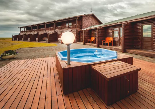 Outdoor hot tub on a wooden platform, next to a lodge building