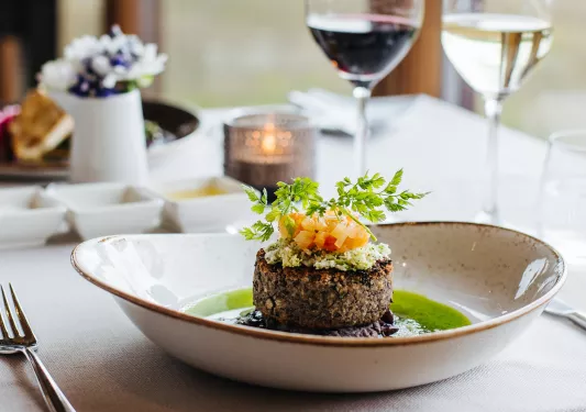 Plate with a small piece of steak in the center, on a table with a  tablecloth