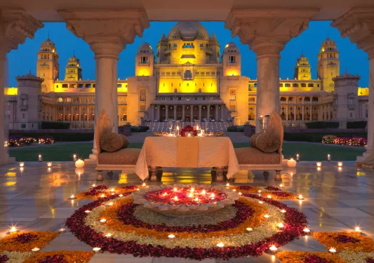Outdoor area looking out to a palace, with flowers and large cushioned chairs
