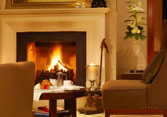 Leather couch in front of a white fireplace, with pastries and fruit on a circular coffee table
