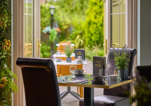 Dining area with tall, leather chairs with an open door in the background