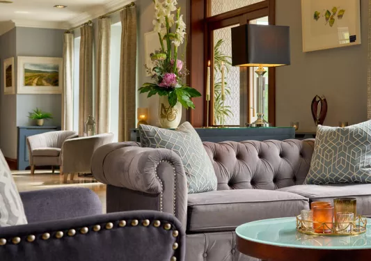 Seating area with cushioned, gray sofa with a circular glass table in front