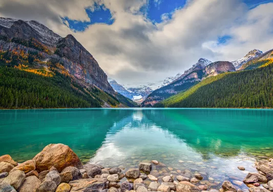 Open lake with large mountains and tall trees in the distance