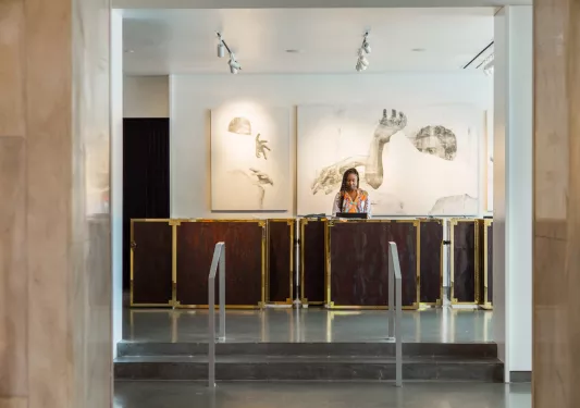 Woman standing at a reception table in front of a large hallway and small staircase