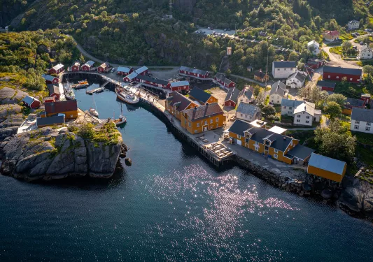 Sky view of orange and red buildings next to a cliff and a body of water