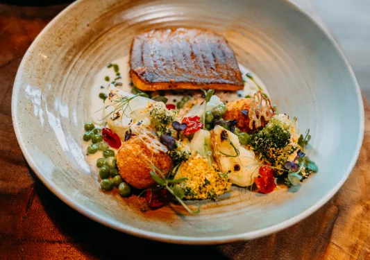 Plate of grilled fish and decorated, prepared vegetables