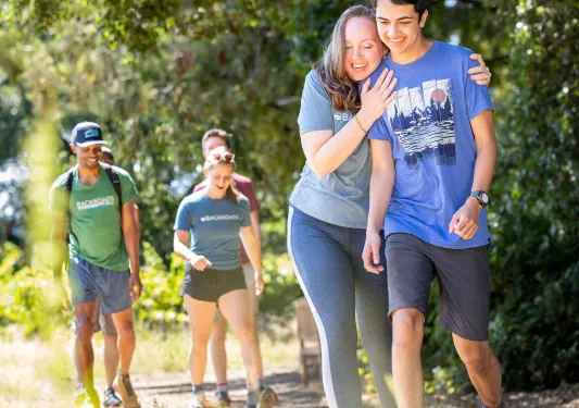 Woman hugging a man while walking on a gravel trail