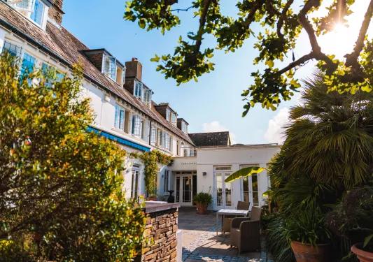 Outdoor patio of a hotel building surrounded by tall green plants