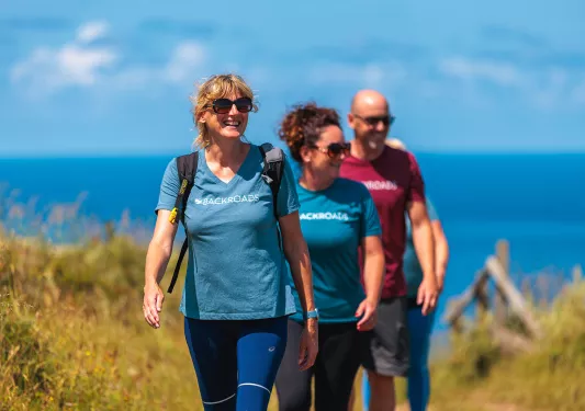 Two women and one man walking on a trail