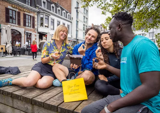 Two men and two women enjoy pastries on a bench