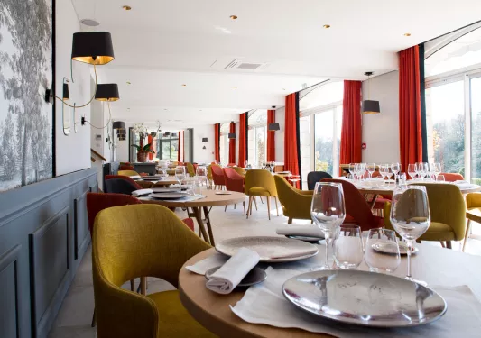 Long dining area with wine glasses and plates on each table