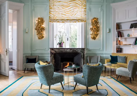 Two blue, cushioned chairs in front of a fireplace in a lobby