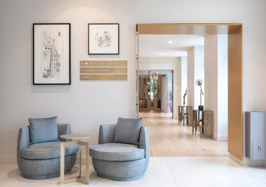 Indoor lobby with a long hallway to the right, and cushioned chairs on the left