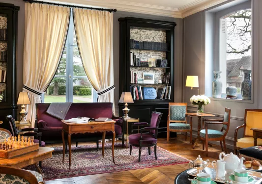 Library and lounge with tall, black book shelves and burgundy velvet sofas