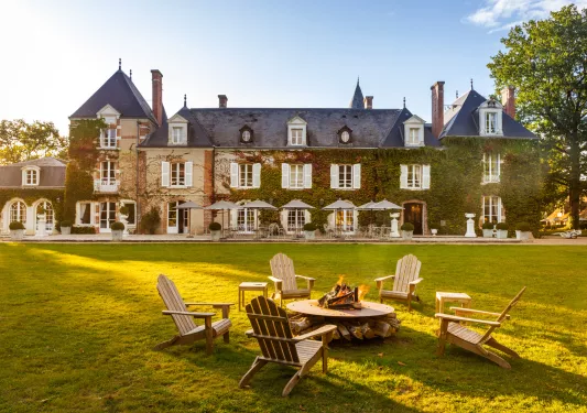 Exterior view of tan and blue hotel building, covered in green plants with a grass field in front