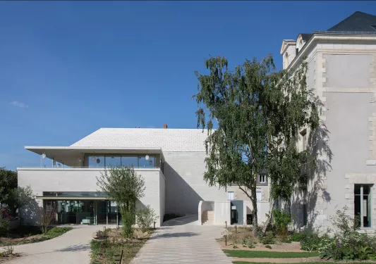 Modern, white building with large, glass doors and trees in front