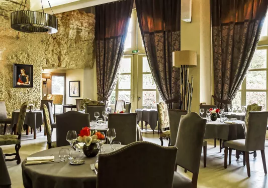 Indoor dining area with large flower-patterned curtains, with gray suede chairs