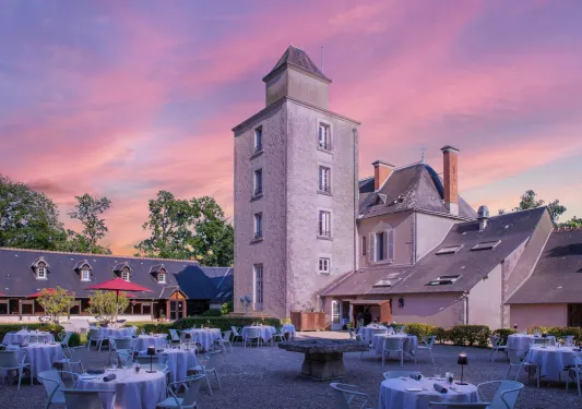 Outdoor couryard filled with dining tables and chairs, with stone buildings in the background