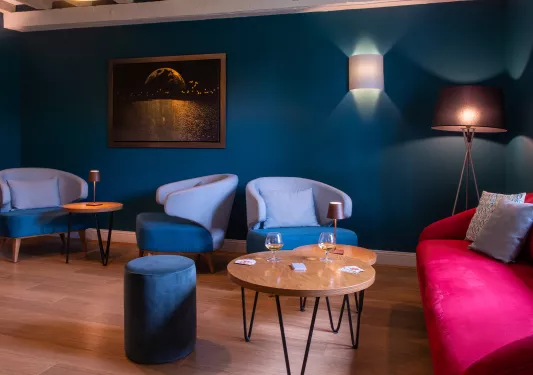 Lounge with blue cushioned seats and wine glasses on wooden tables