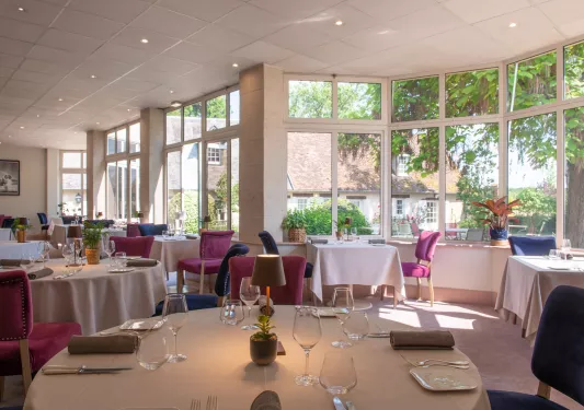 Indoor dining area with large, open windows and cushioned red and blue seats