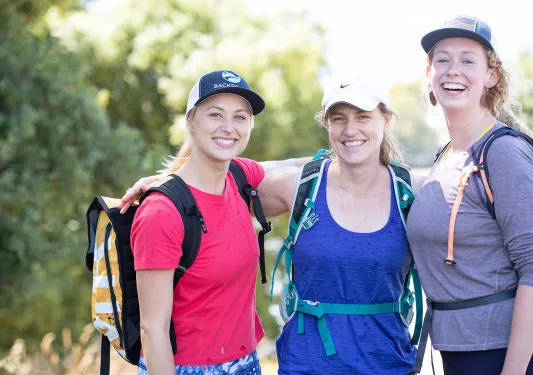 Three female hikers with arms around their shoulders