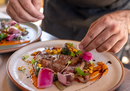 hands plating a steak