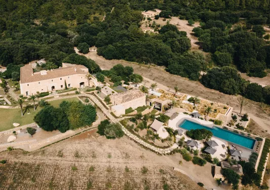 Top view of large white buildings and an outdoor pool surrounded by trees