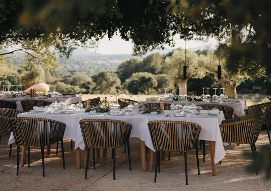 Outdoor dining area with white tablecloths and wooden chairs
