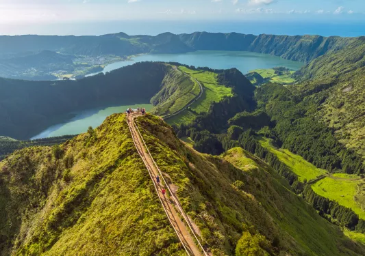 Sky view of a long path that sits on top of a long, grass-covered cliff