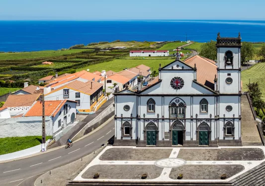 Large church building in the middle of a small town, with an ocean in the background