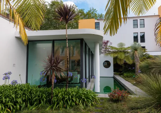 Building with large, glass walls with plants and palm trees outside
