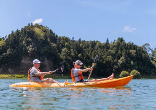 Man and woman inside of a kayak, paddling in the middle of a lake