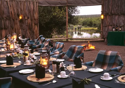 Outdoor dining area with tables and chairs with a quilted blanket over each chair
