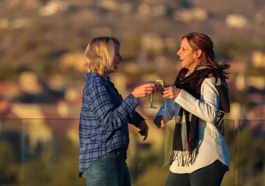Two women smiling while holding martini glasses