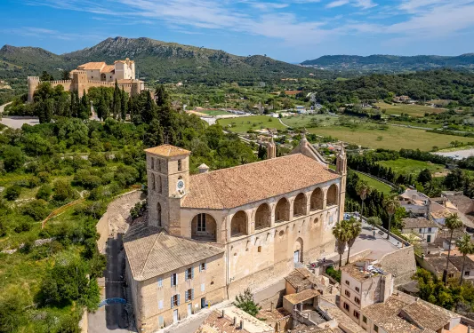 Top view of stone, yellow building with archways and trees behind the building