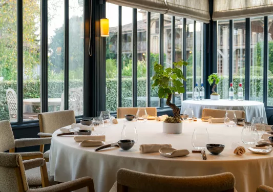 Large circular dining table with cutlery and wine glasses around the table