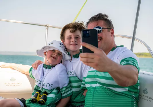 Dad and two sons taking a selfie on a boat