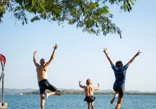 Man and two kids jumps into the ocean