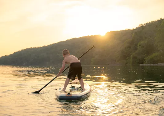 Child paddle boarding in the middle of a lake
