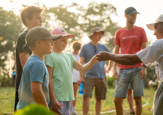 Man handing a flower to two kids