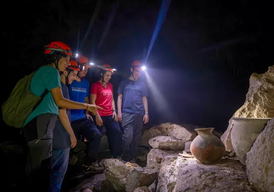 Group of hikers with headlamps looking at rocks in a cave